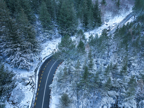 Aerial view of a winding asphalt road cutting through dense snow covered pine forests in the Serra da Estrela mountains Unhais da Serra Castelo Branco Portugal. Aerial view of a winding asphalt road cutting through dense snow covered pine forests in the Serra da Estrela mountains Unhais da Serra Castelo Branco Portugal.