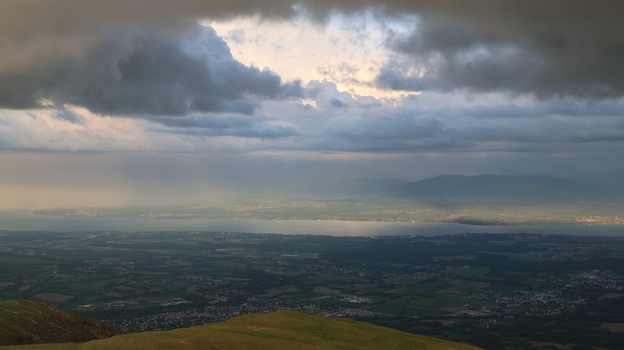 Aerial view of Le Colomby de Gex overlooking the valley and Lake Geneva under dramatic storm clouds with light rays in Echenevex Auvergne Rhone Alpes France. Aerial view of Le Colomby de Gex overlooking the valley and Lake Geneva under dramatic storm clouds with light rays in Echenevex Auvergne Rhone Alpes France.
