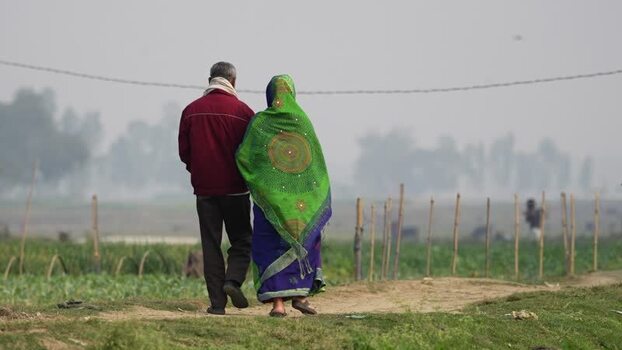 View of a couple walking through rural fields in Bogura Bangladesh.
