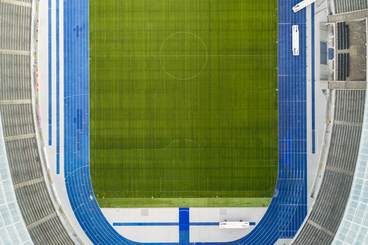 Berlin Germany 26 September 2026 Aerial view of Olympiastadion Berlin featuring the green football pitch surrounded by a vibrant blue running track and stadium seating.