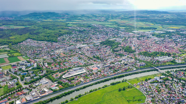Aerial view of the town of Forchheim featuring the Main Danube Canal residential neighborhoods and lush green hills under a cloudy sky in Forchheim Bavaria Germany. Aerial view of the town of Forchheim featuring the Main Danube Canal residential neighborhoods and lush green hills under a cloudy sky in Forchheim Bavaria Germany.