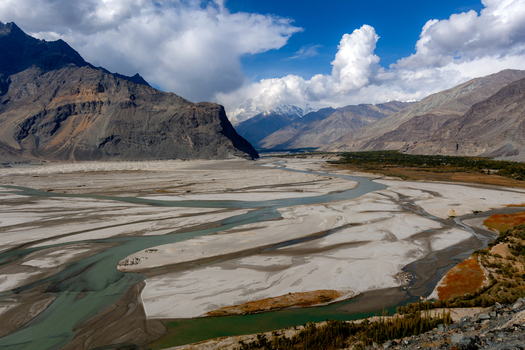 Aerial view of the Shigar Delta where the meandering Shigar River meets the Indus River surrounded by rugged mountains and autumn foliage in Shigar Gilgit Baltistan Pakistan. Aerial view of the Shigar Delta where the meandering Shigar River meets the Indus River surrounded by rugged mountains and autumn foliage in Shigar Gilgit Baltistan Pakistan.