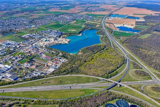 Aerial view of the vibrant blue waters of a quarry lake contrasting with the surrounding industrial area and lush greenery Sausheim Grand Est France.