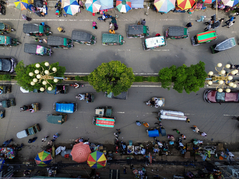 Rajshahi Bangladesh 26 September 2026 Aerial view of a busy street with numerous auto rickshaws pedestrians and colorful market umbrellas under green trees. Rajshahi Bangladesh 26 September 2026 Aerial view of a busy street with numerous auto rickshaws pedestrians and colorful market umbrellas under green trees.