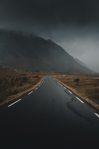View of a road winding through the dramatic landscape of Lofoten under a dark moody sky in Nordland Norway. View of a road winding through the dramatic landscape of Lofoten under a dark moody sky in Nordland Norway.