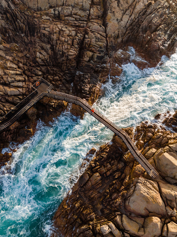 Aerial view of Canal Rocks Bridge spanning over turquoise ocean waves crashing against rugged granite rocks in Yallingup Western Australia Australia. Aerial view of Canal Rocks Bridge spanning over turquoise ocean waves crashing against rugged granite rocks in Yallingup Western Australia Australia.
