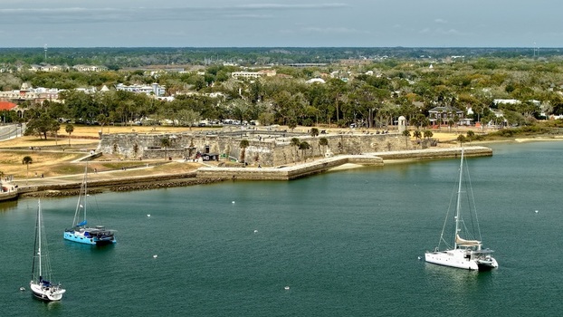 Aerial view of Castillo de San Marcos historic fort with sailboats on the Matanzas River and lush green trees in St. Augustine Florida United States.