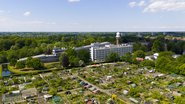 Aerial view of the KNMI building complex and radar tower surrounded by lush green trees and community allotment gardens in De Bilt Utrecht Netherlands. Aerial view of the KNMI building complex and radar tower surrounded by lush green trees and community allotment gardens in De Bilt Utrecht Netherlands.