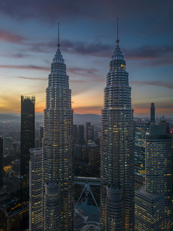 Kuala Lumpur Malaysia 11 March 2026 Aerial view of Petronas Twin Towers illuminated at sunset with the city skyline and colorful clouds in the background.