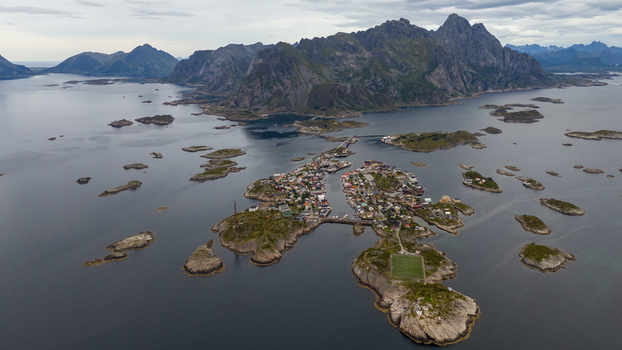 Aerial view of the fishing village of Henningsvaer with its iconic football pitch on a rocky island surrounded by dramatic mountains and deep blue waters in Henningsvaer Nordland Norway. Aerial view of the fishing village of Henningsvaer with its iconic football pitch on a rocky island surrounded by dramatic mountains and deep blue waters in Henningsvaer Nordland Norway.