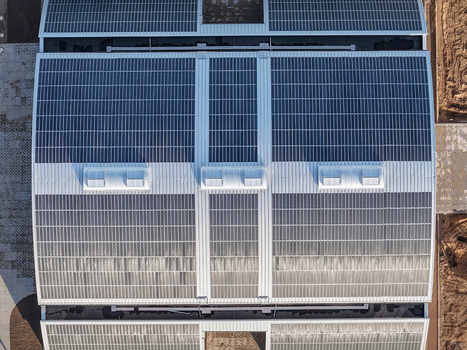 Aerial view of a large industrial building roof covered with extensive solar panel arrays and skylights in Uckermark Brandenburg Germany. Aerial view of a large industrial building roof covered with extensive solar panel arrays and skylights in Uckermark Brandenburg Germany.