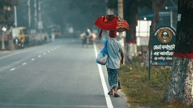View of a man carrying mats on his head along a road Bangladesh. View of a man carrying mats on his head along a road Bangladesh.