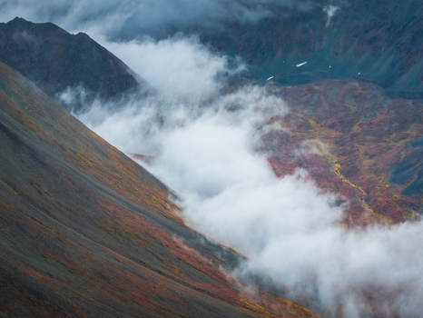 Aerial view of Denali Highway with autumn foliage and mist clinging to the rocky mountain slopes in Cantwell Alaska United States.