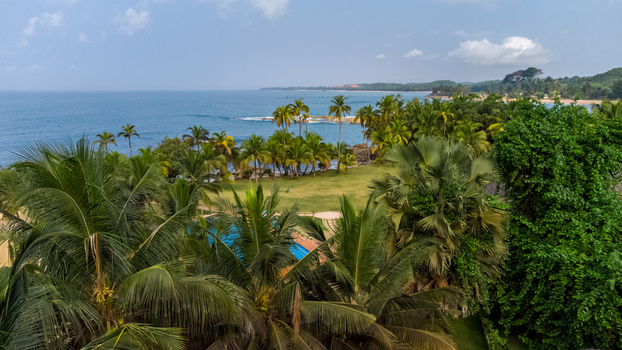 Axim Western Region Ghana 09 February 2023 Aerial view of Lou Moon Resort Eco Luxury featuring lush palm trees a swimming pool and the scenic coastline of the Atlantic Ocean. Axim Western Region Ghana 09 February 2023 Aerial view of Lou Moon Resort Eco Luxury featuring lush palm trees a swimming pool and the scenic coastline of the Atlantic Ocean.