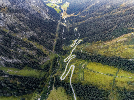 Aerial view of the winding Silvretta Hochalpenstrasse mountain road surrounded by dense pine forests and lush green alpine slopes in the valley Partenen Vorarlberg Austria. Aerial view of the winding Silvretta Hochalpenstrasse mountain road surrounded by dense pine forests and lush green alpine slopes in the valley Partenen Vorarlberg Austria.
