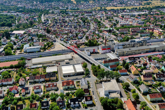 Aerial view of the red Piastenbrucke bridge crossing over railway tracks and the urban landscape with residential houses and industrial buildings in Forchheim Bayern Germany.