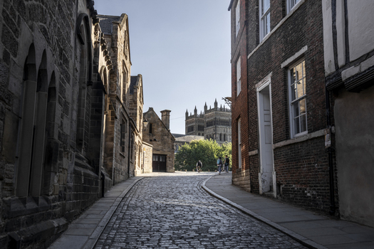 Durham England United Kingdom 13 July 2026 View of Durham Cathedral from a historic cobblestone street with brick buildings and people walking in the distance. Durham England United Kingdom 13 July 2026 View of Durham Cathedral from a historic cobblestone street with brick buildings and people walking in the distance.