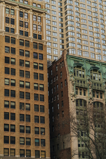 View of historic brick buildings with ornate green copper architectural details and a modern skyscraper in the background in New York New York United States.