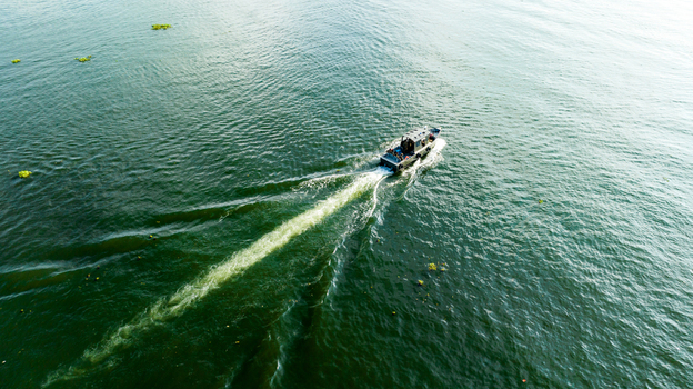 Rangamati Chittagong Division Bangladesh 19 October 2022 Aerial view of a small boat traveling across the calm waters of Kaptai Lake leaving a white wake behind.