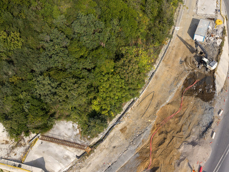 Aerial view of a construction site with an excavator working on a dirt road adjacent to a dense forest in Istanbul Istanbul Turkiye.