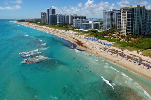 Aerial view of Singer Island beach and high rise condominiums along the turquoise Atlantic Ocean waters with people on the sand in Riviera Beach Florida United States. Aerial view of Singer Island beach and high rise condominiums along the turquoise Atlantic Ocean waters with people on the sand in Riviera Beach Florida United States.