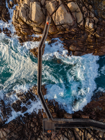 Aerial view of Canal Rocks Bridge with turquoise waves crashing against rugged granite rock formations in Yallingup Western Australia Australia. Aerial view of Canal Rocks Bridge with turquoise waves crashing against rugged granite rock formations in Yallingup Western Australia Australia.