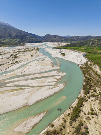 Aerial view of Vjosa Wild River National Park with a braided river channel turquoise water and expansive gravel banks in Permet Gjirokaster County Albania. Aerial view of Vjosa Wild River National Park with a braided river channel turquoise water and expansive gravel banks in Permet Gjirokaster County Albania.