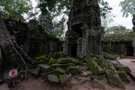 View of the ancient stone ruins of Ta Prohm temple overgrown with massive tree roots and lush green moss in the jungle setting of Krong Siem Reap Siem Reap Province Cambodia. View of the ancient stone ruins of Ta Prohm temple overgrown with massive tree roots and lush green moss in the jungle setting of Krong Siem Reap Siem Reap Province Cambodia.
