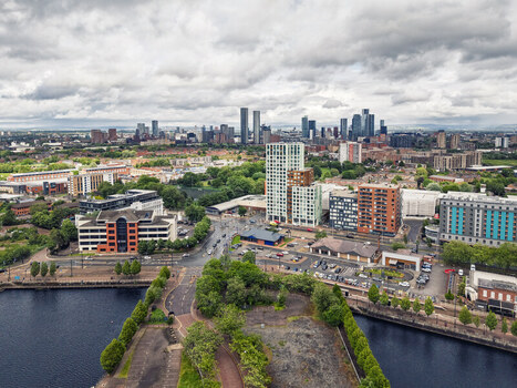 Aerial view of MediaCityUK with modern high rise buildings waterfront areas and the Manchester skyline in the background under a cloudy sky in Salford England United Kingdom. Aerial view of MediaCityUK with modern high rise buildings waterfront areas and the Manchester skyline in the background under a cloudy sky in Salford England United Kingdom.