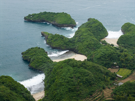 Aerial view of Sedahan Beach s dramatic cliffs meet the turquoise sea where lush greenery contrasts with the white sand and crashing waves Gunungkidul Regency Indonesia. Aerial view of Sedahan Beach s dramatic cliffs meet the turquoise sea where lush greenery contrasts with the white sand and crashing waves Gunungkidul Regency Indonesia.