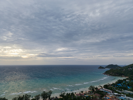 Aerial view of the coastline of Ko Tao with lush tropical vegetation sandy beach and turquoise sea under a dramatic cloudy sky in Ko Tao Surat Thani Thailand.