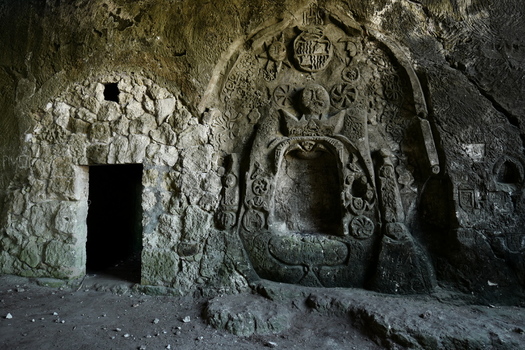 View of ancient stone carvings and a dark cave entrance in Mallorca Balearic Islands Spain.