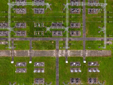 Aerial view of an electrical substation featuring power transformers metal structures and power lines set against a green grassy field in Gdansk Poland. Aerial view of an electrical substation featuring power transformers metal structures and power lines set against a green grassy field in Gdansk Poland.