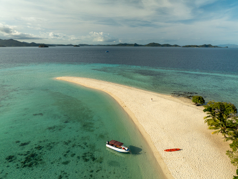 Aerial view of the white sandbar at Malcapuya Island with a boat anchored in turquoise water and a red kayak on the beach in Coron Mimaropa Philippines. Aerial view of the white sandbar at Malcapuya Island with a boat anchored in turquoise water and a red kayak on the beach in Coron Mimaropa Philippines.