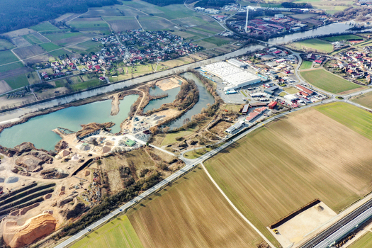 Aerial view of the industrial area and quarry site near the river with agricultural fields and residential houses in Forchheim Bavaria Germany. Aerial view of the industrial area and quarry site near the river with agricultural fields and residential houses in Forchheim Bavaria Germany.