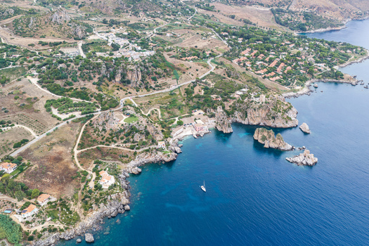Aerial view of Riserva Naturale Orientata dello Zingaro with rugged cliffs turquoise waters a small cove with a boat and Mediterranean vegetation San Vito Lo Capo Sicilia Italy. Aerial view of Riserva Naturale Orientata dello Zingaro with rugged cliffs turquoise waters a small cove with a boat and Mediterranean vegetation San Vito Lo Capo Sicilia Italy.