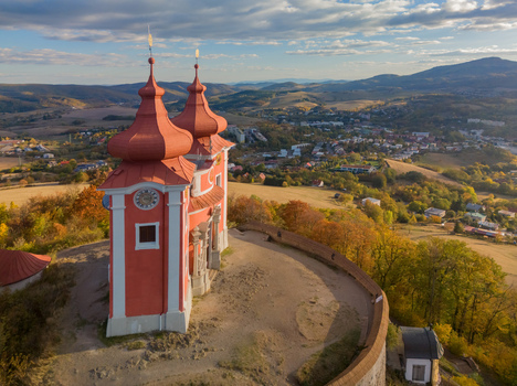 Aerial view of Stiavnicka kalvaria church with red roofs and clock tower overlooking the autumn landscape and town in Banska Stiavnica Banskobystricky kraj Slovakia. Aerial view of Stiavnicka kalvaria church with red roofs and clock tower overlooking the autumn landscape and town in Banska Stiavnica Banskobystricky kraj Slovakia.