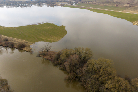 Aerial view of flooded agricultural fields with green grass patches bare trees and muddy river water under an overcast sky Kaniukai Kaunas County Lithuania. Aerial view of flooded agricultural fields with green grass patches bare trees and muddy river water under an overcast sky Kaniukai Kaunas County Lithuania.