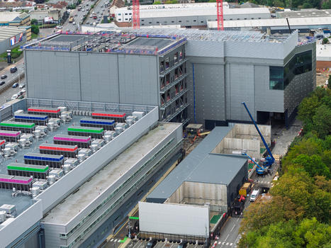 Aerial view of a large data center facility featuring industrial architecture rooftop cooling units and ongoing construction work in the United Kingdom.