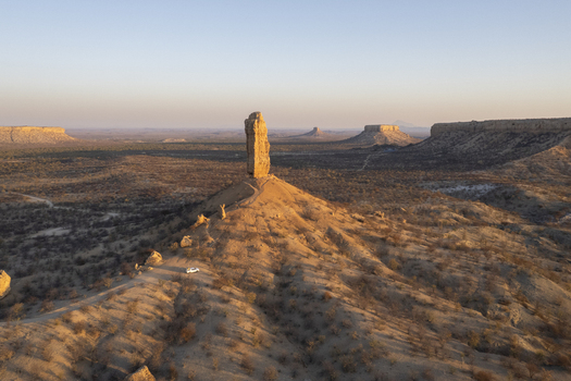Aerial view of a solitary rock formation piercing the vast arid landscape under a soft golden light Namibia. Aerial view of a solitary rock formation piercing the vast arid landscape under a soft golden light Namibia.