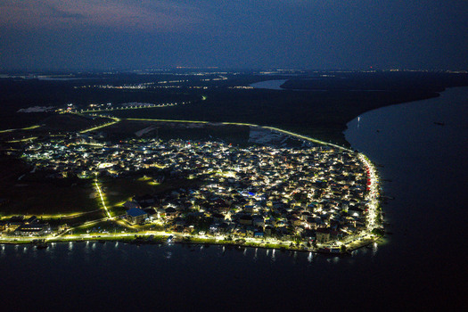 Aerial view of the illuminated town of Opobo Town at night with bright streetlights reflecting along the riverbank and dense residential buildings in Opobo Town Rivers Nigeria. Aerial view of the illuminated town of Opobo Town at night with bright streetlights reflecting along the riverbank and dense residential buildings in Opobo Town Rivers Nigeria.