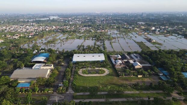 Aerial view of Jakabaring sports complex with a running track and large buildings surrounded by flooded fields and urban landscape in Kecamatan Seberang Ulu I Sumatera Selatan Indonesia. Aerial view of Jakabaring sports complex with a running track and large buildings surrounded by flooded fields and urban landscape in Kecamatan Seberang Ulu I Sumatera Selatan Indonesia.