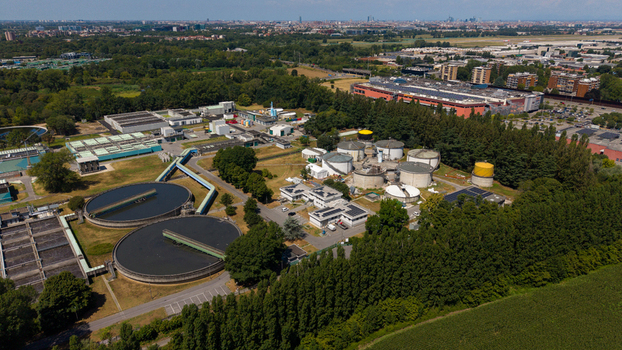 Aerial view of a wastewater treatment plant with circular sedimentation tanks and industrial facilities surrounded by green trees and fields in Milan Lombardy Italy. Aerial view of a wastewater treatment plant with circular sedimentation tanks and industrial facilities surrounded by green trees and fields in Milan Lombardy Italy.