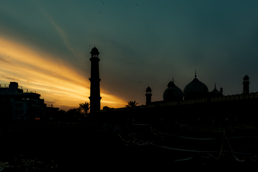 View of the silhouette of Badshahi Mosque with its iconic minarets and domes against a vibrant golden sunset sky in Lahore Punjab Pakistan. View of the silhouette of Badshahi Mosque with its iconic minarets and domes against a vibrant golden sunset sky in Lahore Punjab Pakistan.
