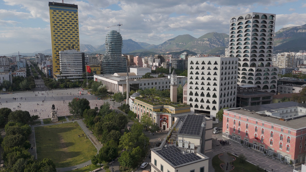 Aerial view of Skanderbeg Square featuring the historic clock tower modern high rise buildings and surrounding urban architecture under a clear sky in Tirane Tirana County Albania.