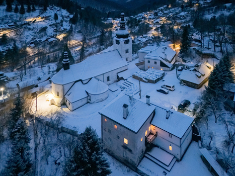 Aerial view of the historic church and snow covered rooftops of the mountain village at twilight in Spania Dolina Banska Bystrica Region Slovakia. Aerial view of the historic church and snow covered rooftops of the mountain village at twilight in Spania Dolina Banska Bystrica Region Slovakia.