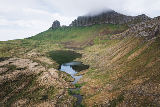 Aerial view of Hornstrandir Nature Reserve with rugged mountain peaks shrouded in mist and a calm lake reflecting the sky Isafjordur Isafjardarbaer Iceland. Aerial view of Hornstrandir Nature Reserve with rugged mountain peaks shrouded in mist and a calm lake reflecting the sky Isafjordur Isafjardarbaer Iceland.