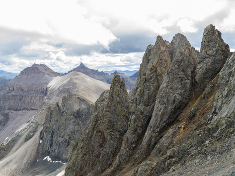 Aerial view of Mount Sneffels in the San Juan Mountain Range featuring jagged rocky peaks and steep slopes under a cloudy sky in Ouray Colorado United States. Aerial view of Mount Sneffels in the San Juan Mountain Range featuring jagged rocky peaks and steep slopes under a cloudy sky in Ouray Colorado United States.