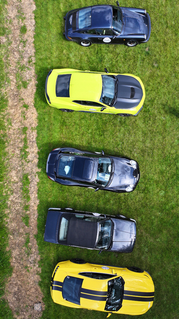 La Chapelle de Guinchay France 01 June 2024 Aerial view of five colorful sports and vintage cars parked in a row on a green lawn next to a dirt path. La Chapelle de Guinchay France 01 June 2024 Aerial view of five colorful sports and vintage cars parked in a row on a green lawn next to a dirt path.