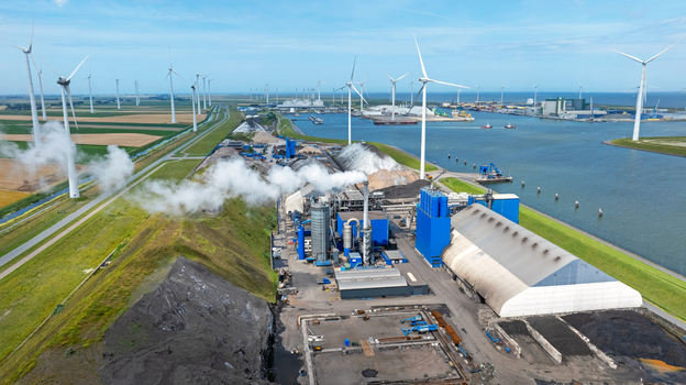 Aerial view of an industrial facility with wind turbines smoke stacks and storage buildings located along the coast in Eemshaven Groningen Netherlands. Aerial view of an industrial facility with wind turbines smoke stacks and storage buildings located along the coast in Eemshaven Groningen Netherlands.